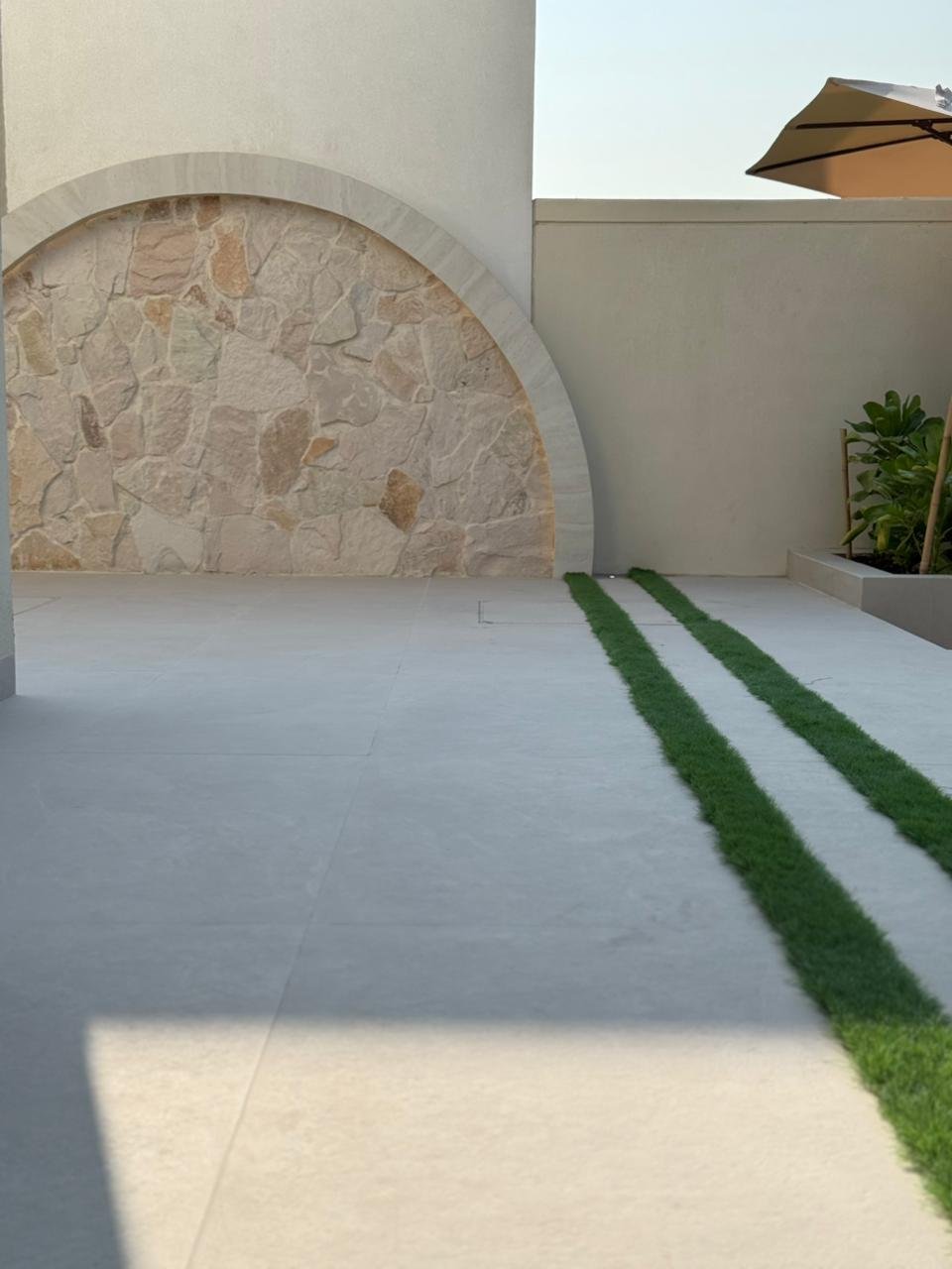 Stone arch detail with artificial turf stripe and planting