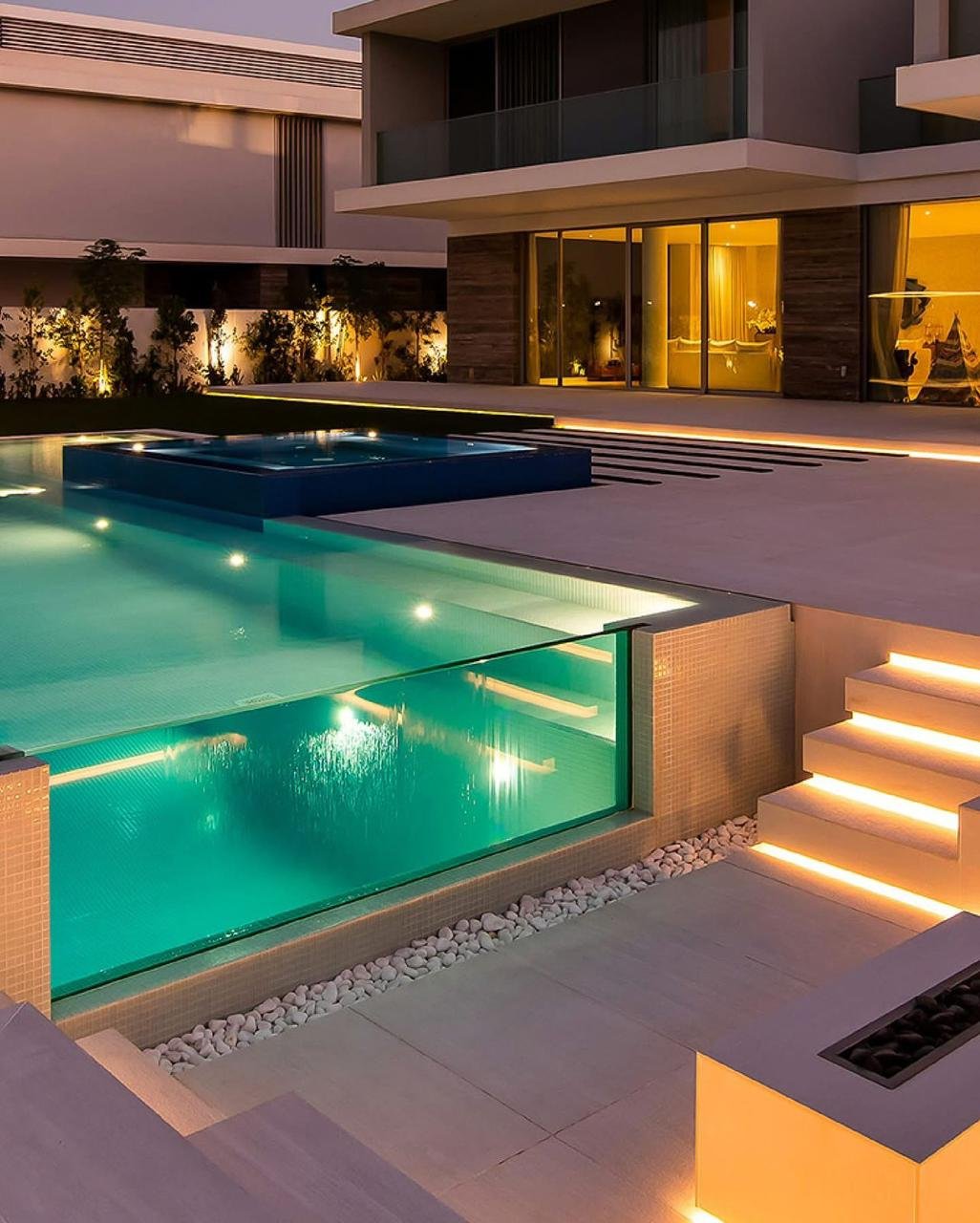 Glass-panel pool with illuminated steps at night