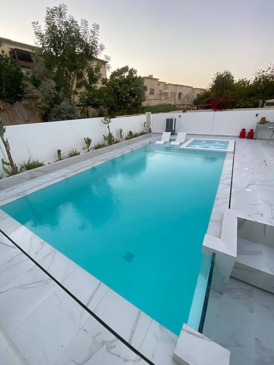 Large luxury pool with palms, lounge chairs and pergola