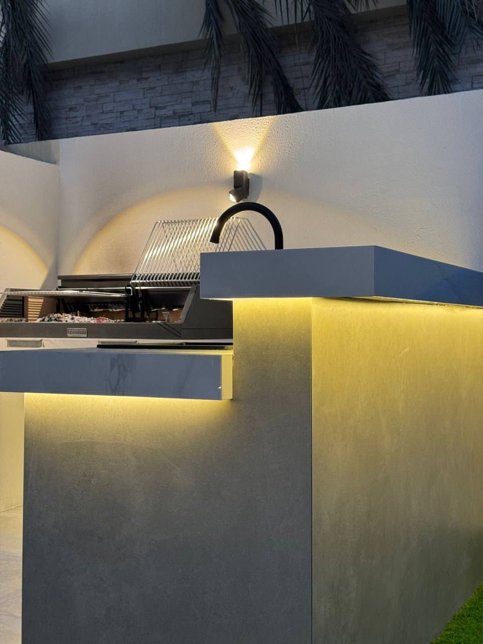 Pool with illuminated waterfall feature and coloured lighting at night