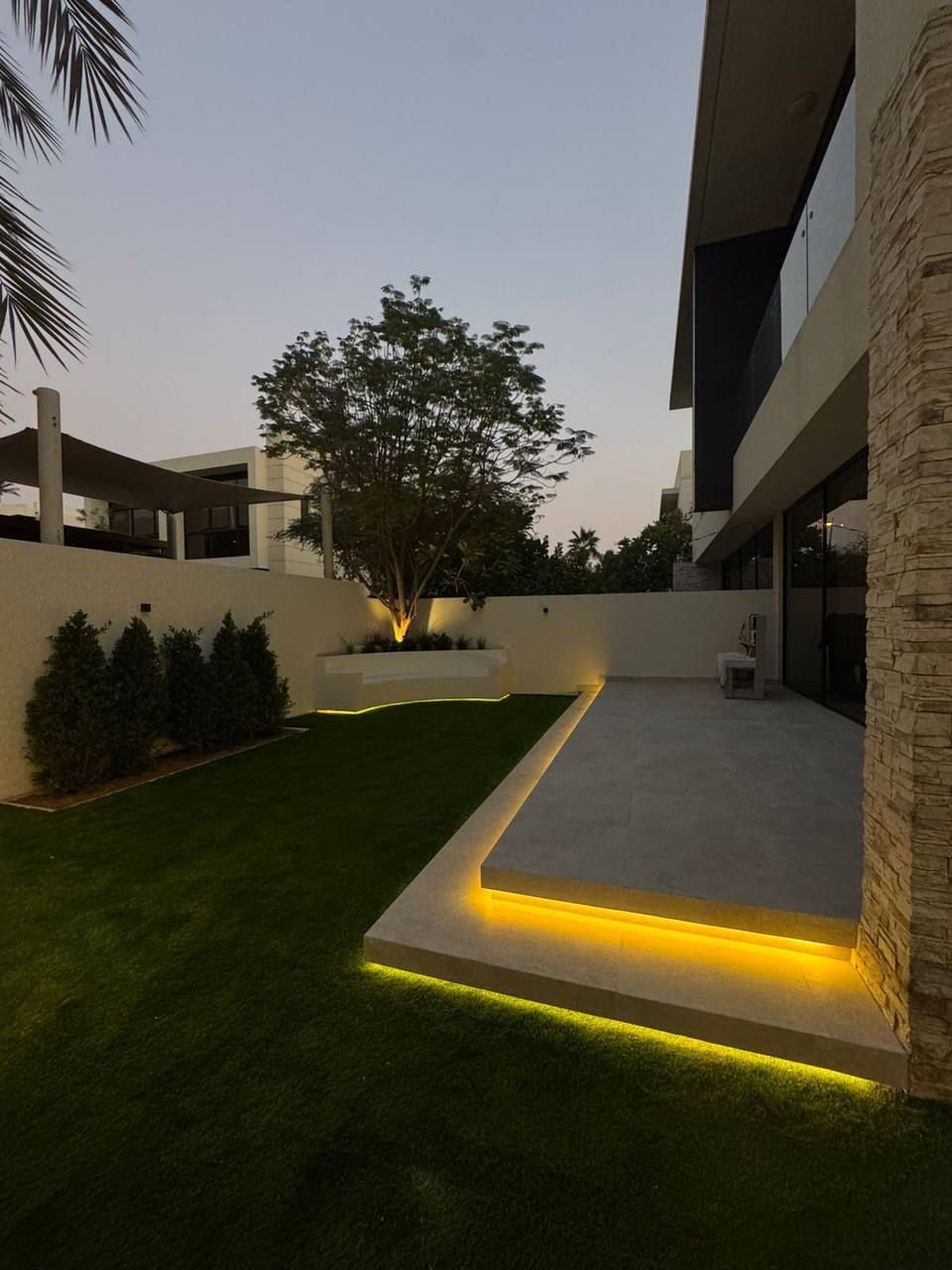Detail of outdoor BBQ kitchen with LED strip and black tap at night